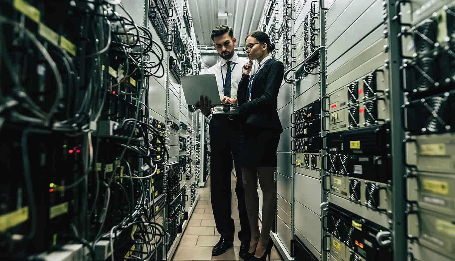Technicians in data center examining servers showing the importance of finding legacy applications to prevent data breach