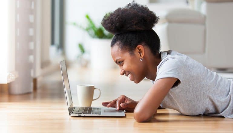African American woman using a laptop in her living room showing need to redevelop website for security and business needs