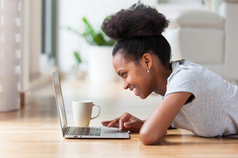 African American woman using a laptop in her living room showing need to redevelop website for security and business needs