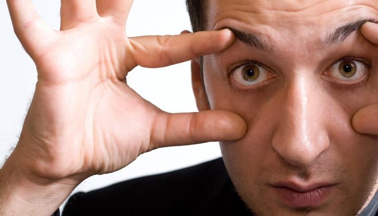 Close-up portrait of businessman with eyes wide open looking at cyber security statistics