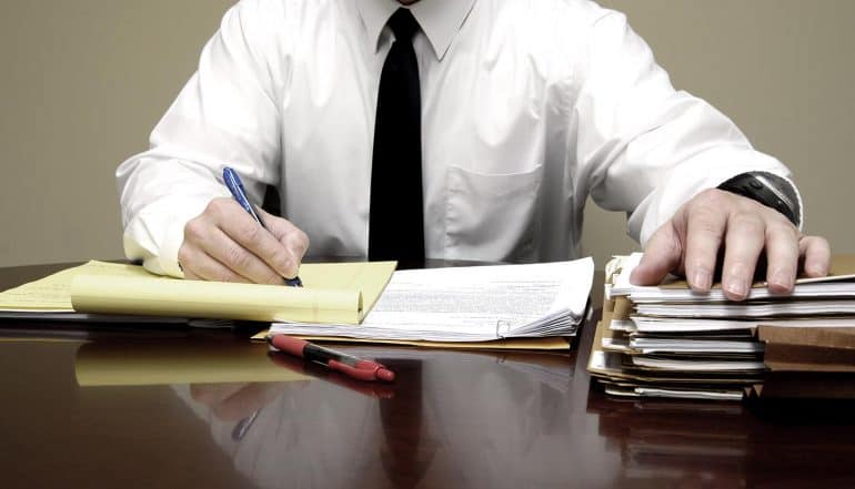 Businessman working at desk showing the things to include in an appropriate cybersecurity policy