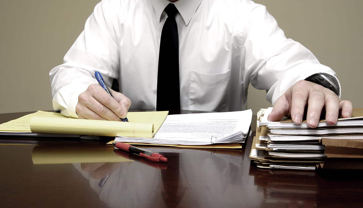 Businessman working at desk showing the things to include in an appropriate cybersecurity policy