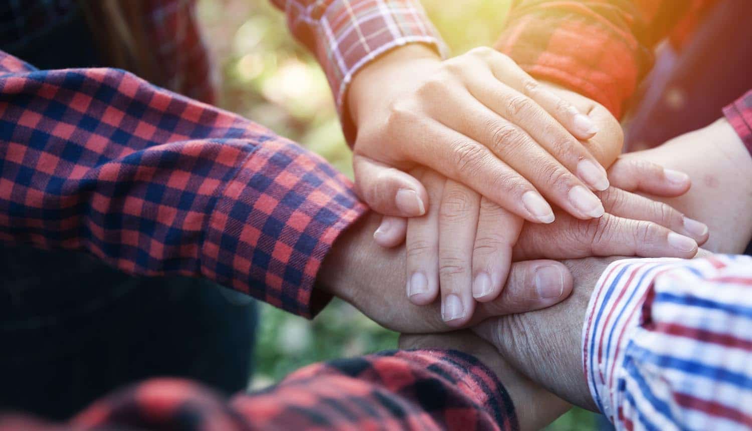 Hands piled in a group showing the interview with Groupon’s global privacy and regulatory managing counsel on how the company enforces privacy without having a CPO