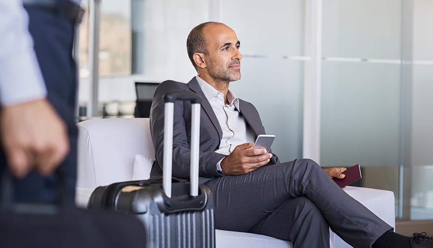 Businessman waiting in airport showing the risks of visual hacking for business travelers