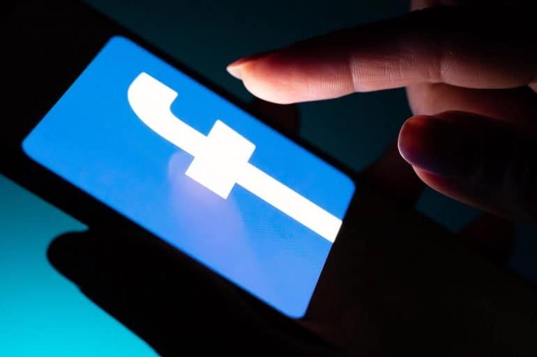 Man touching Facebook app on mobile showing potential privacy implications with Facebook’s Libra cryptocurrency