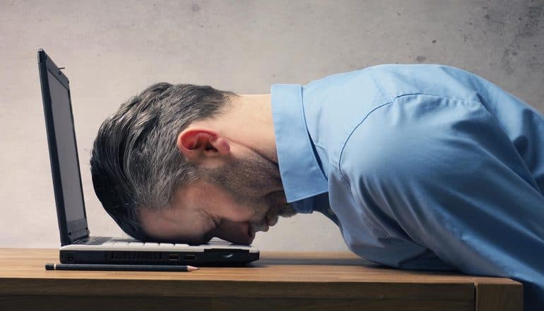 Handsome business man sleeping on a laptop showing how small mistakes can lead to major data breaches