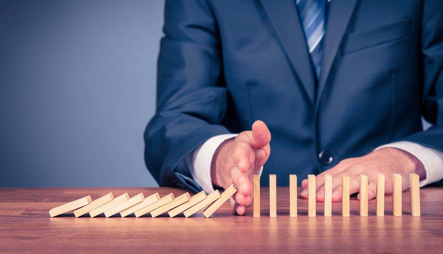 Businessman stopping domino effect showing small vendors may not be the most vulnerable targets in supply chain security