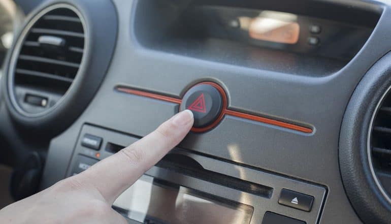 Woman inside car pressing hazard lights button showing the threats of cyber attacks on connected cars