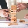 Businessmen playing dominoes block game showing different ways to run risk mitigation to manage security threats