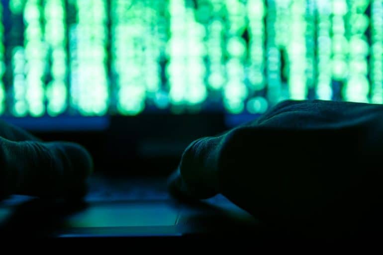 Hacker working on laptop showing the aftermath questions over Capital One data breach