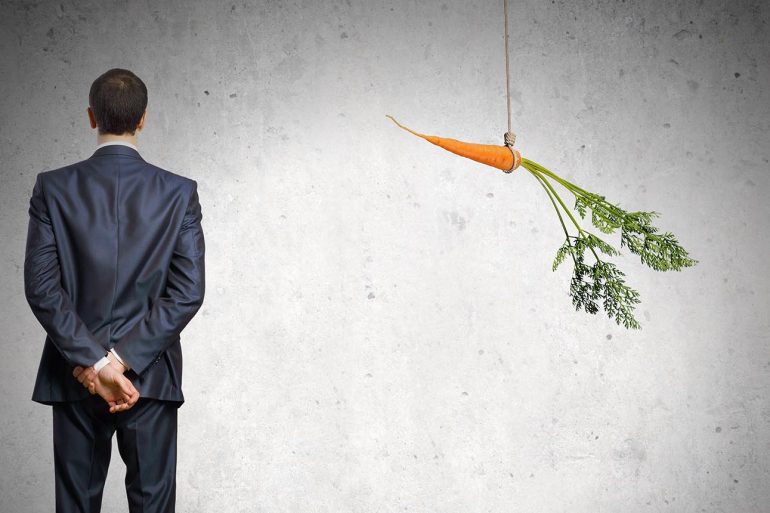 Businessman standing next to dangling carrot showing how cyber insurance providers incentivize clients to buy from specific vendors