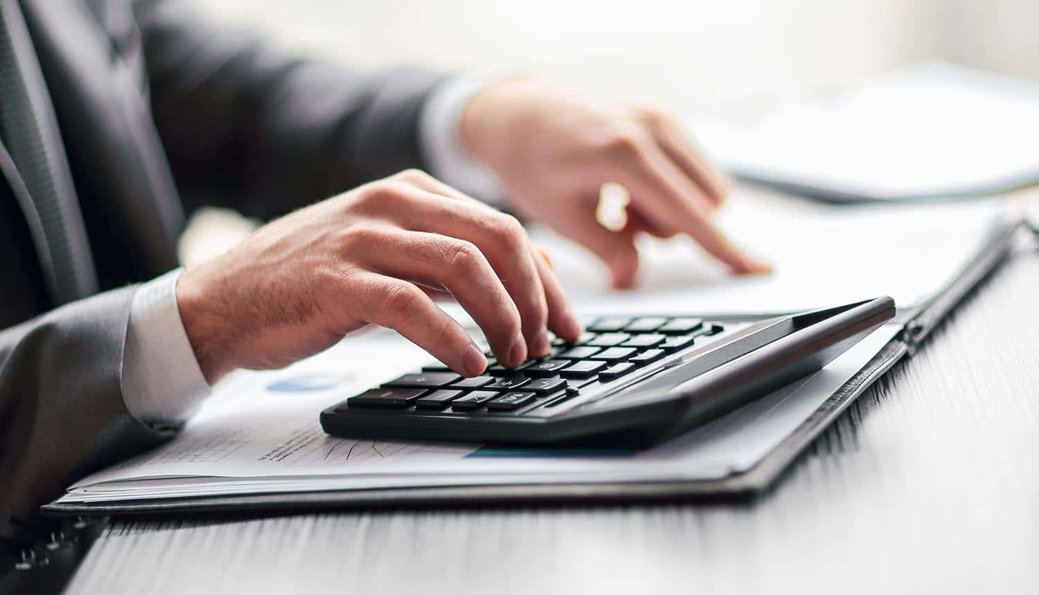 Man using calculator to calculate costs showing initial CCPA compliance costs of $55 billion estimated in new report