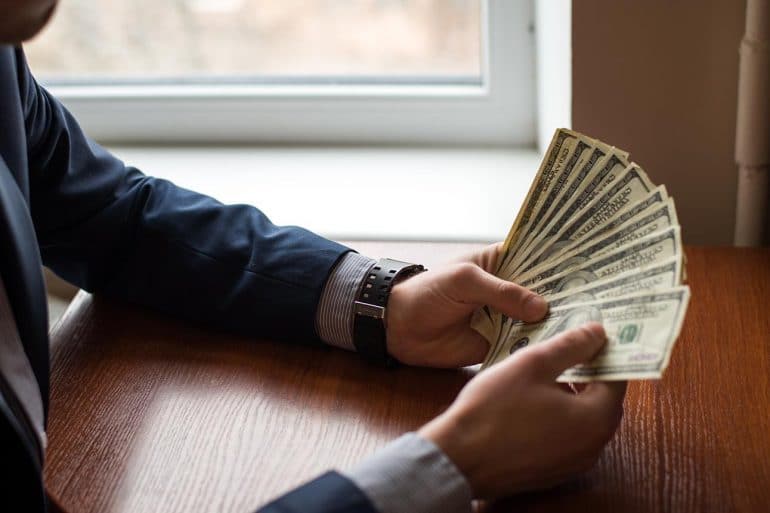 Businessman hand holding money showing conflict between data privacy and anti-money laundering