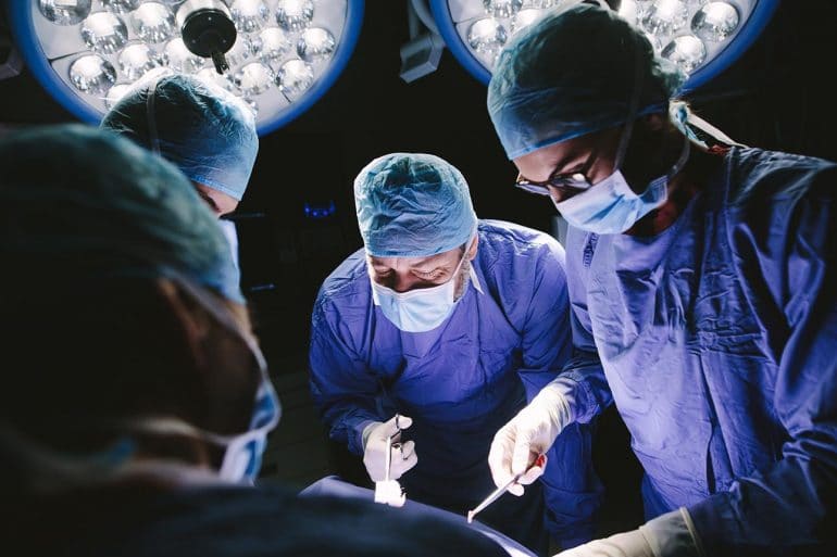 Team of professional surgeons in operation room showing link between data breaches and hospital mortality rates