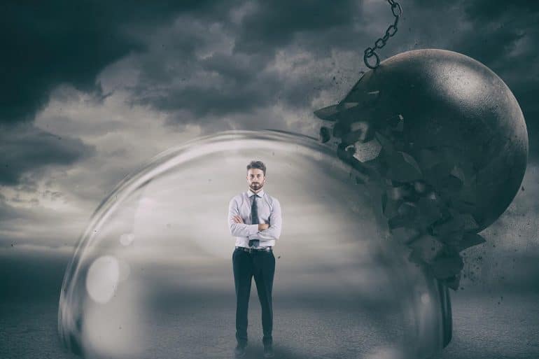 Businessman inside a shield dome during a storm showing the need to have a good crisis plan to manage threats