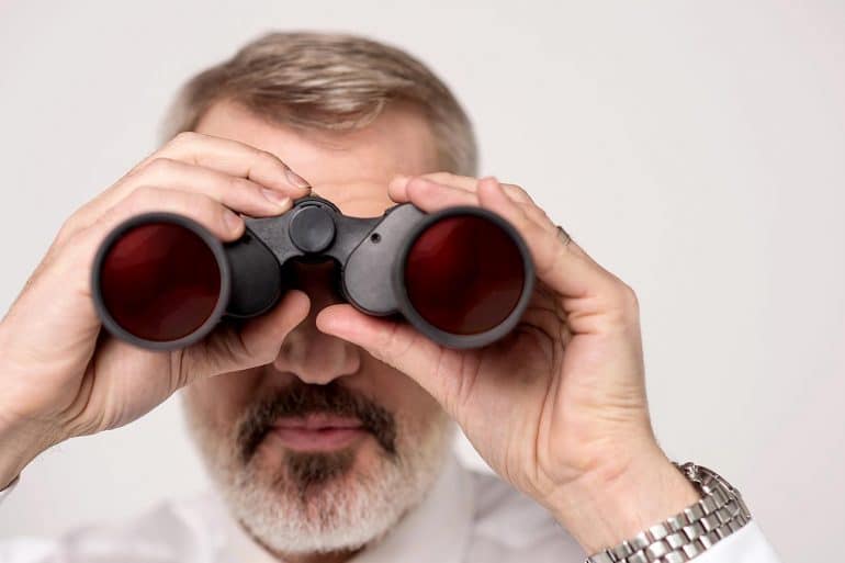 Man seeing through binoculars showing cyber security landscape in 2020 and beyond