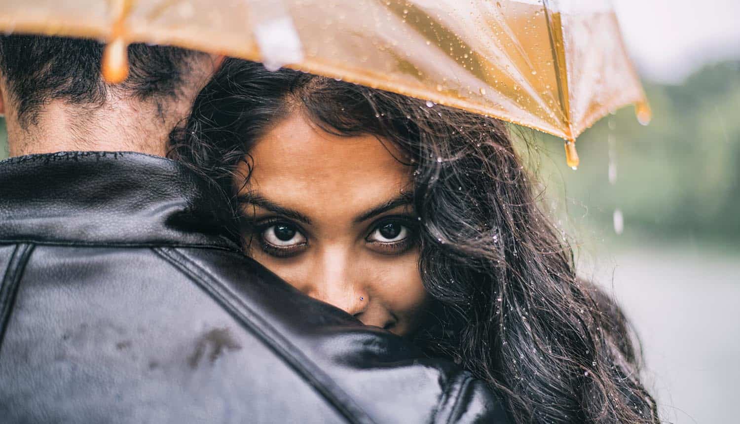 Lovers hugging under the umbrella on a rainy day showing scammers breaking hearts on Valentine's Day