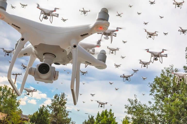 Dozens of drones swarm in the cloudy sky