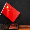 China flag next to laptop showing Chinese hackers on a massive cyber espionage campaign
