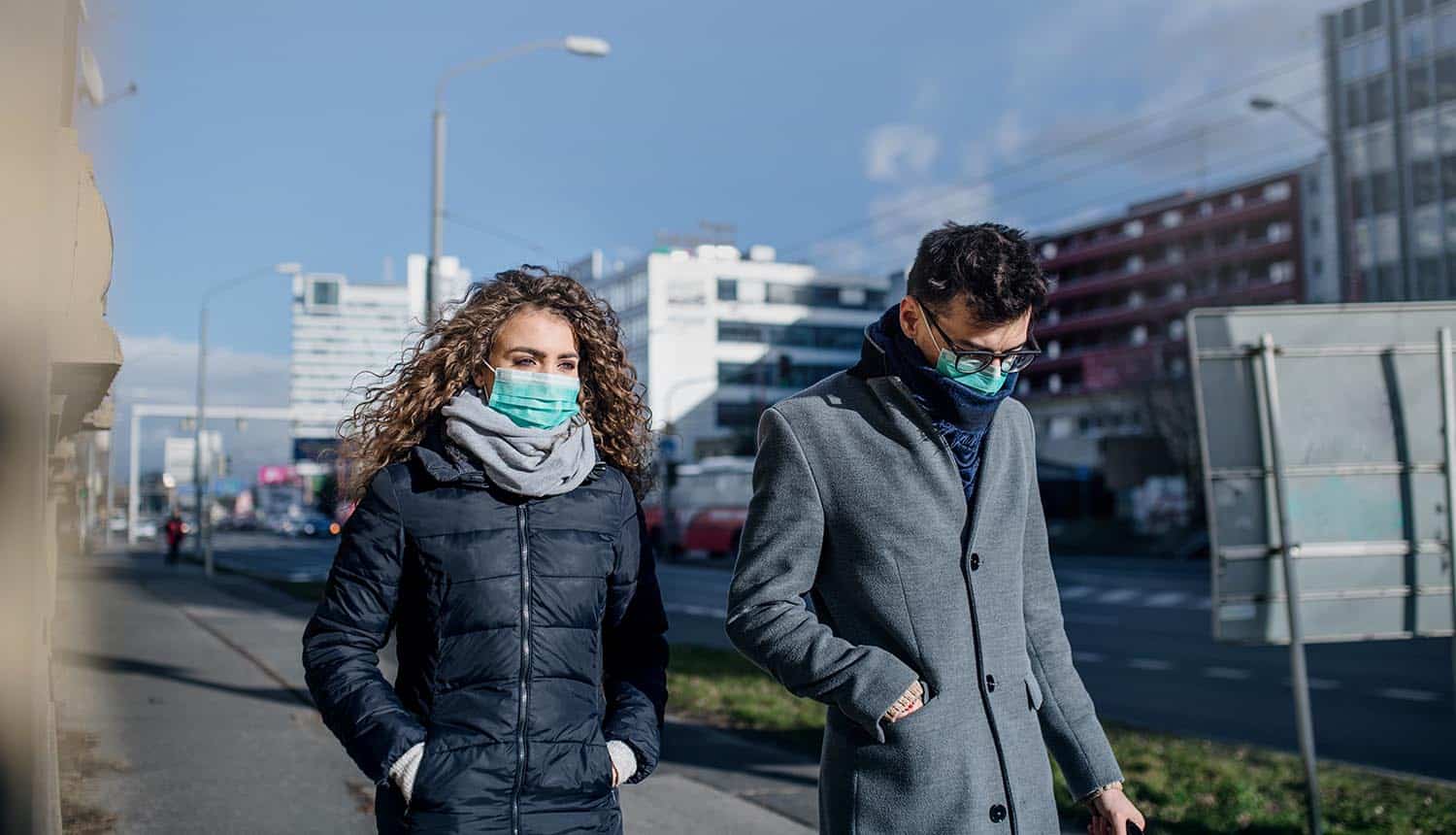 Man and woman wearing face masks on street showing the importance of ethical data privacy in time of COVID-19