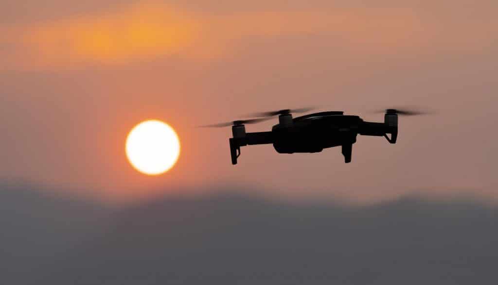 people standing outside while a drone with a camera flies overhead