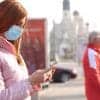 Woman in mask using mobile showing the unreported national security risk of COVID-19 contact tracing apps