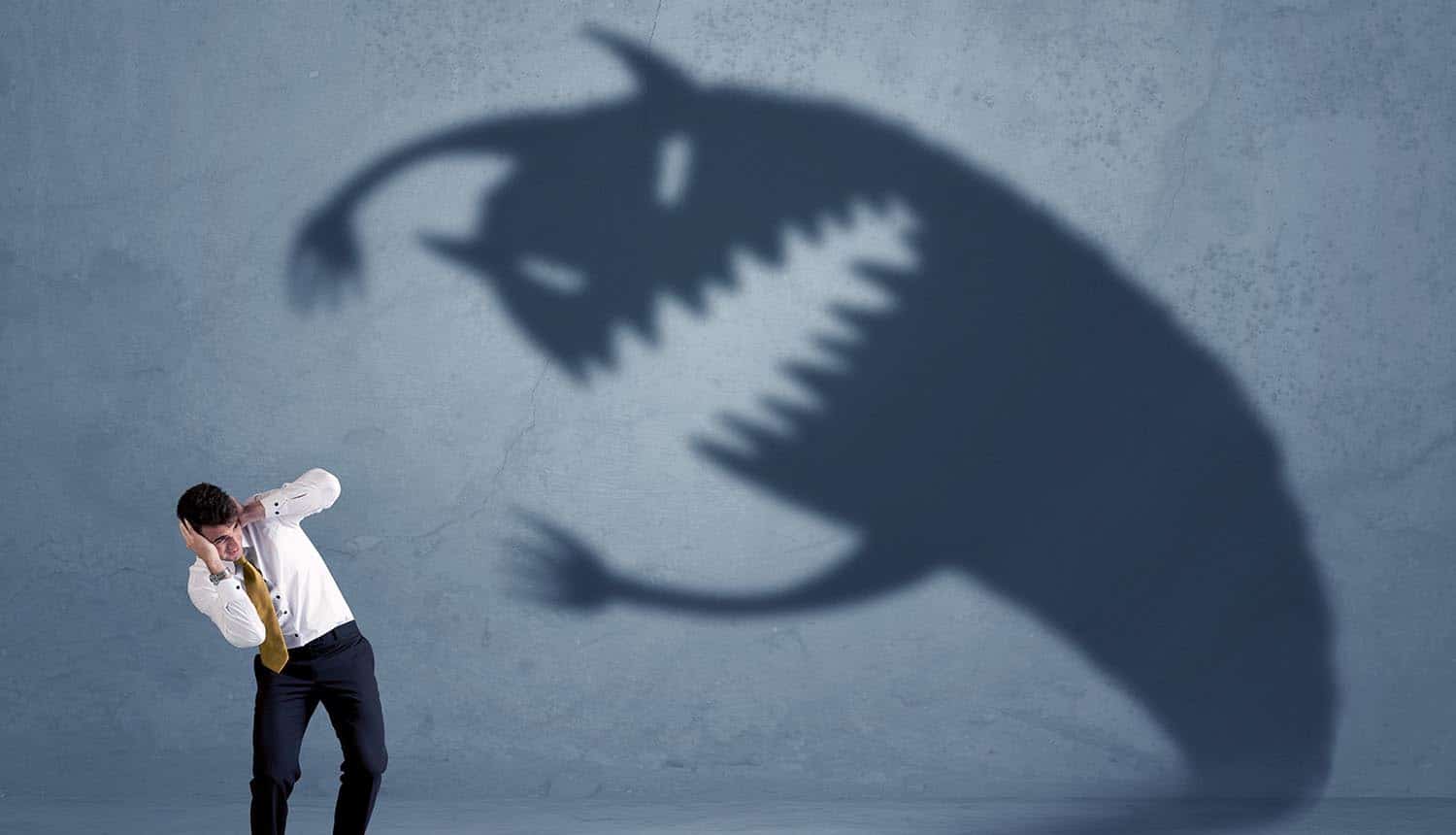 Man afraid of a monster shadow showing the methods to identify and avoid scareware scams