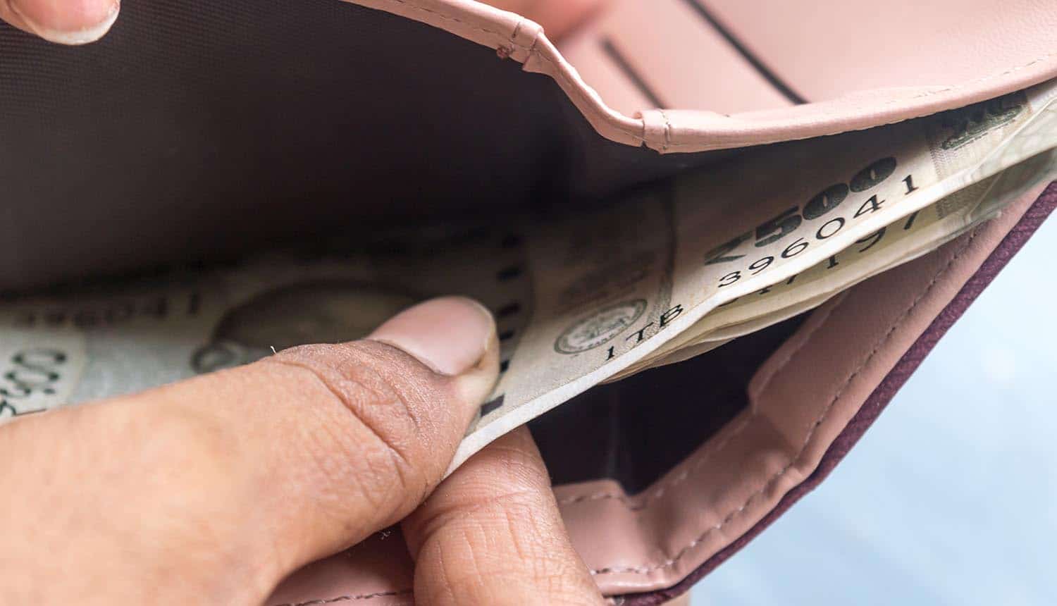 Woman taking out banknotes from leather wallet showing risks in Bitcoin