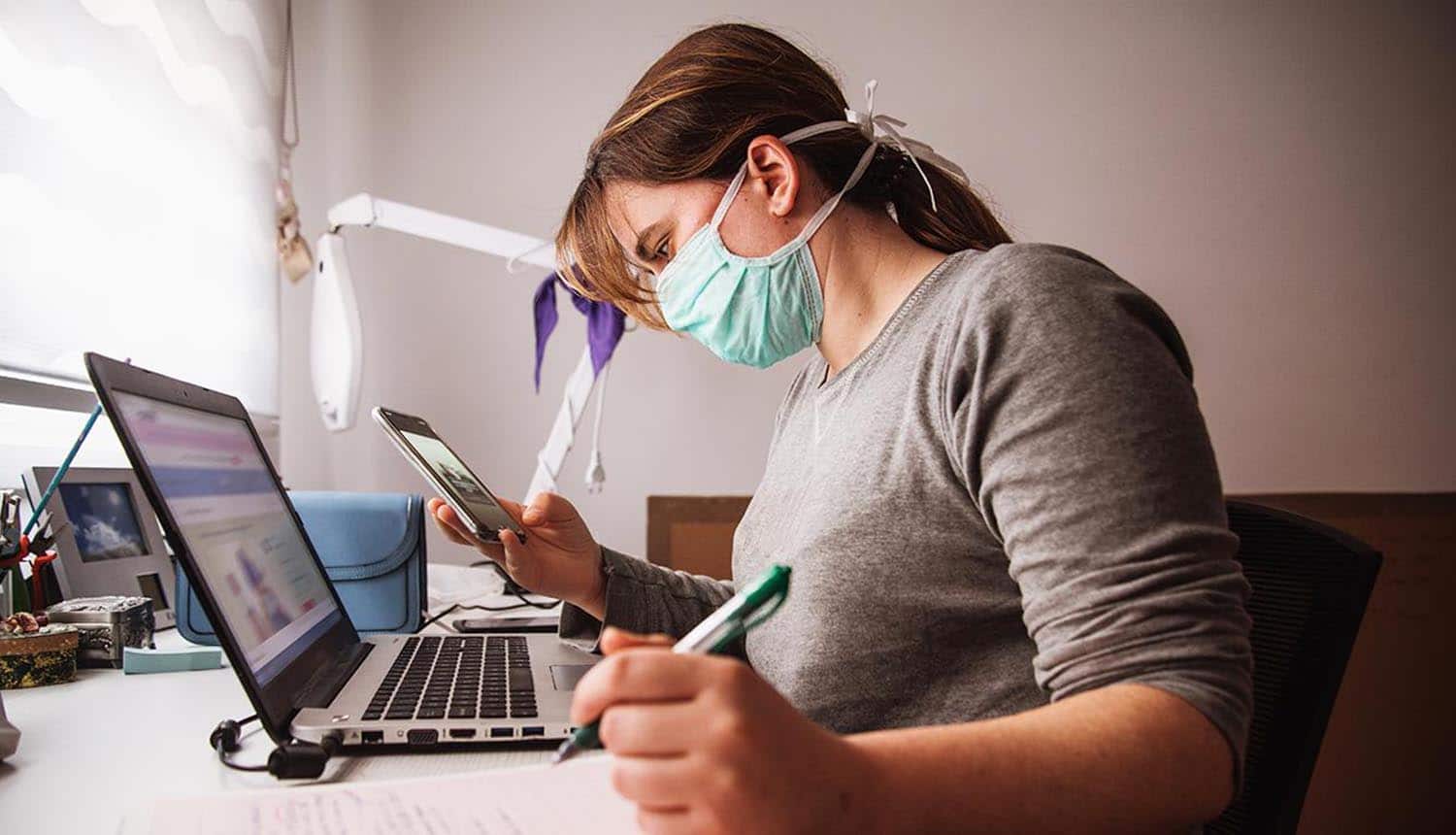 Woman wearing mask and working on laptop showing growth of VPN usage