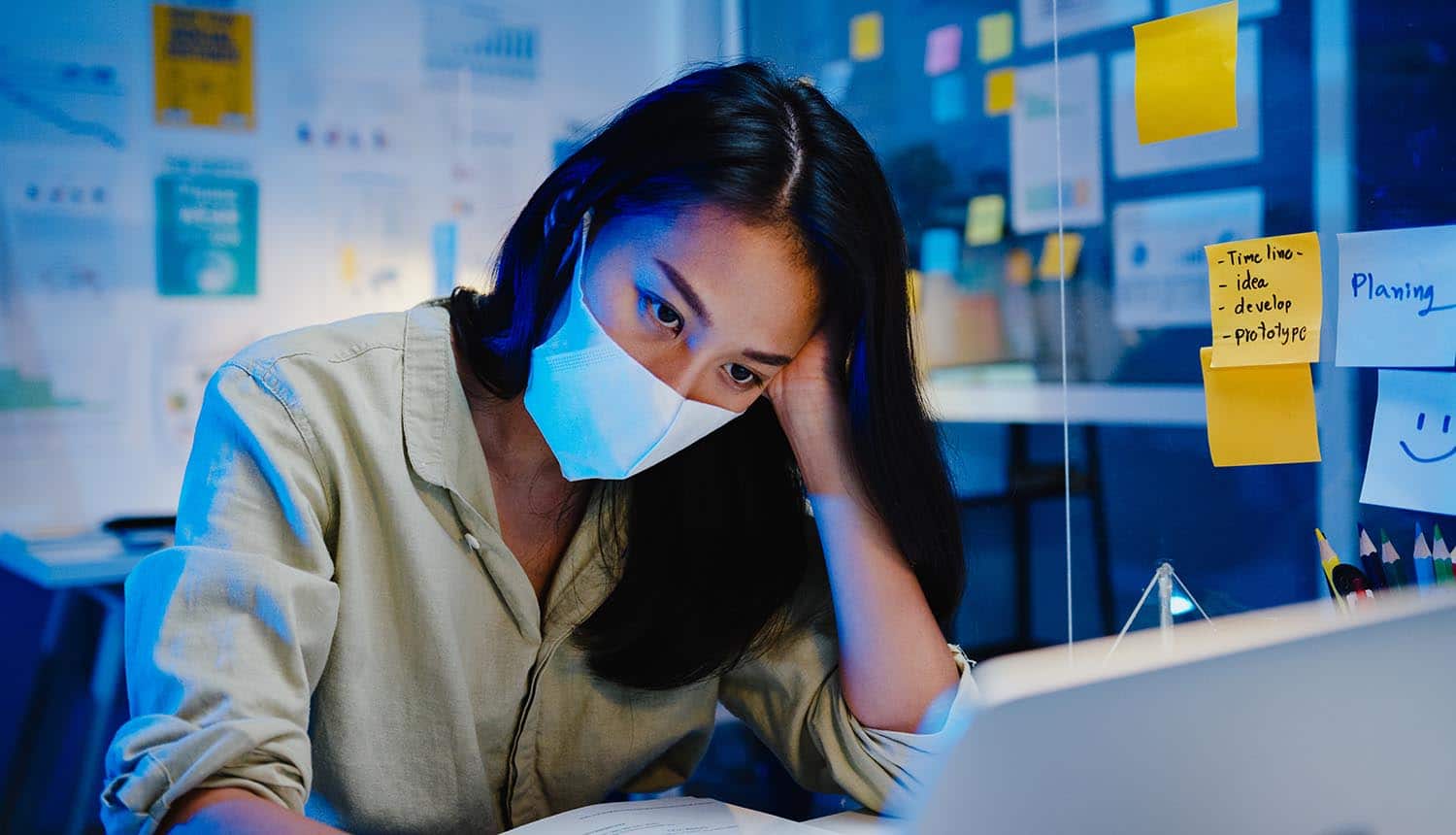 Women with face mask using laptop showing increase cyber attacks on remote work during COVID-19