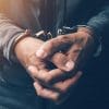 Arrested cyber criminal with handcuffs showing international law enforcement takedown of dark web vendors
