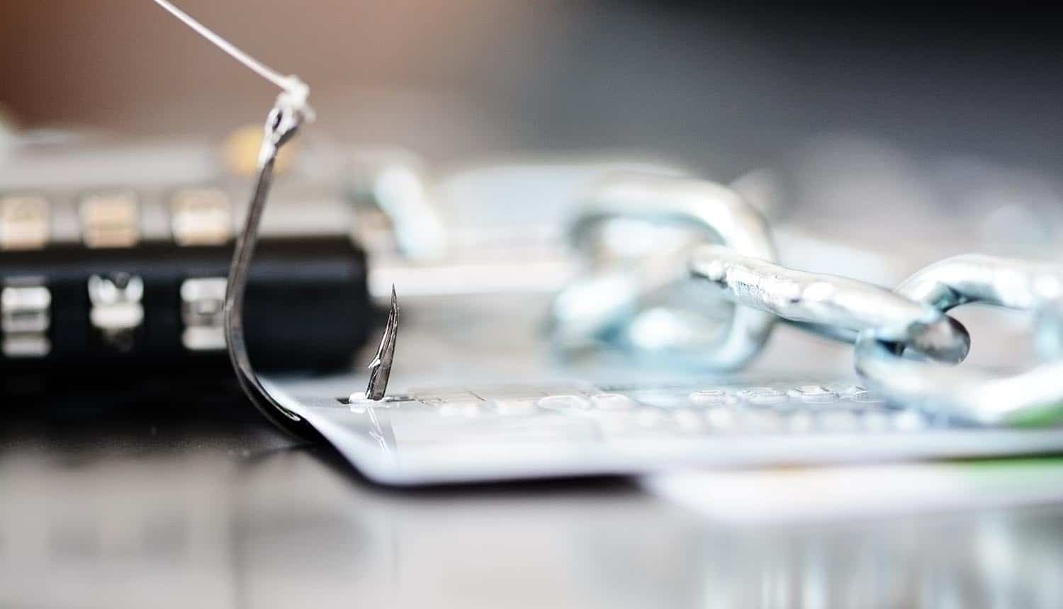 Padlock and chain near credit cards in fishing hook showing phishing attack