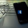 Phone sitting on laptop with Facebook logo reflecting on screen showing antitrust lawsuit to break up Facebook