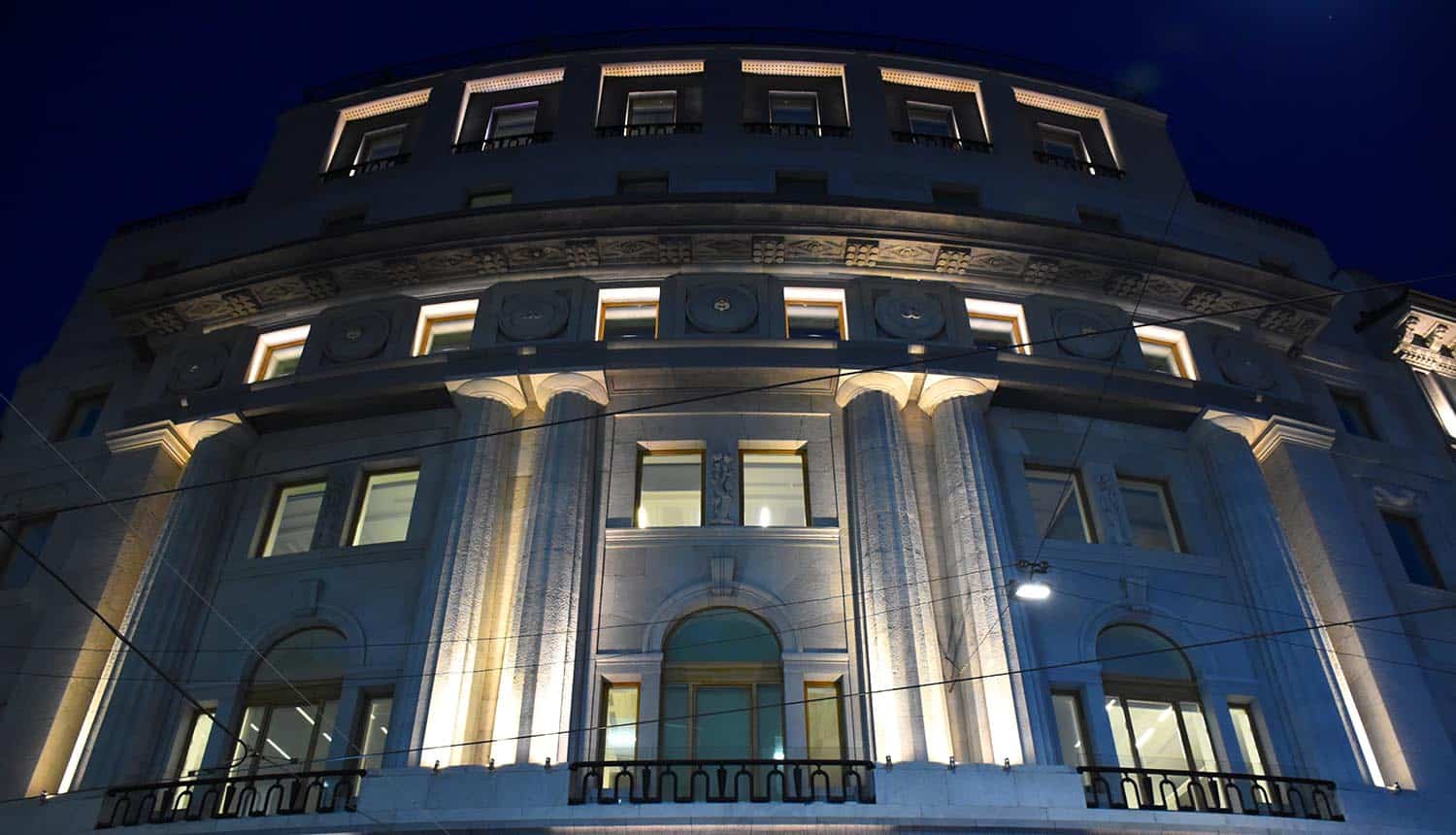 Illuminated building of bank at night night showing financial sector fight against fraud across digital channels