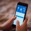 Female hand holding cellphone with starting page of Facebook showing plans to preempt ad tracking notification and Apple IDFA