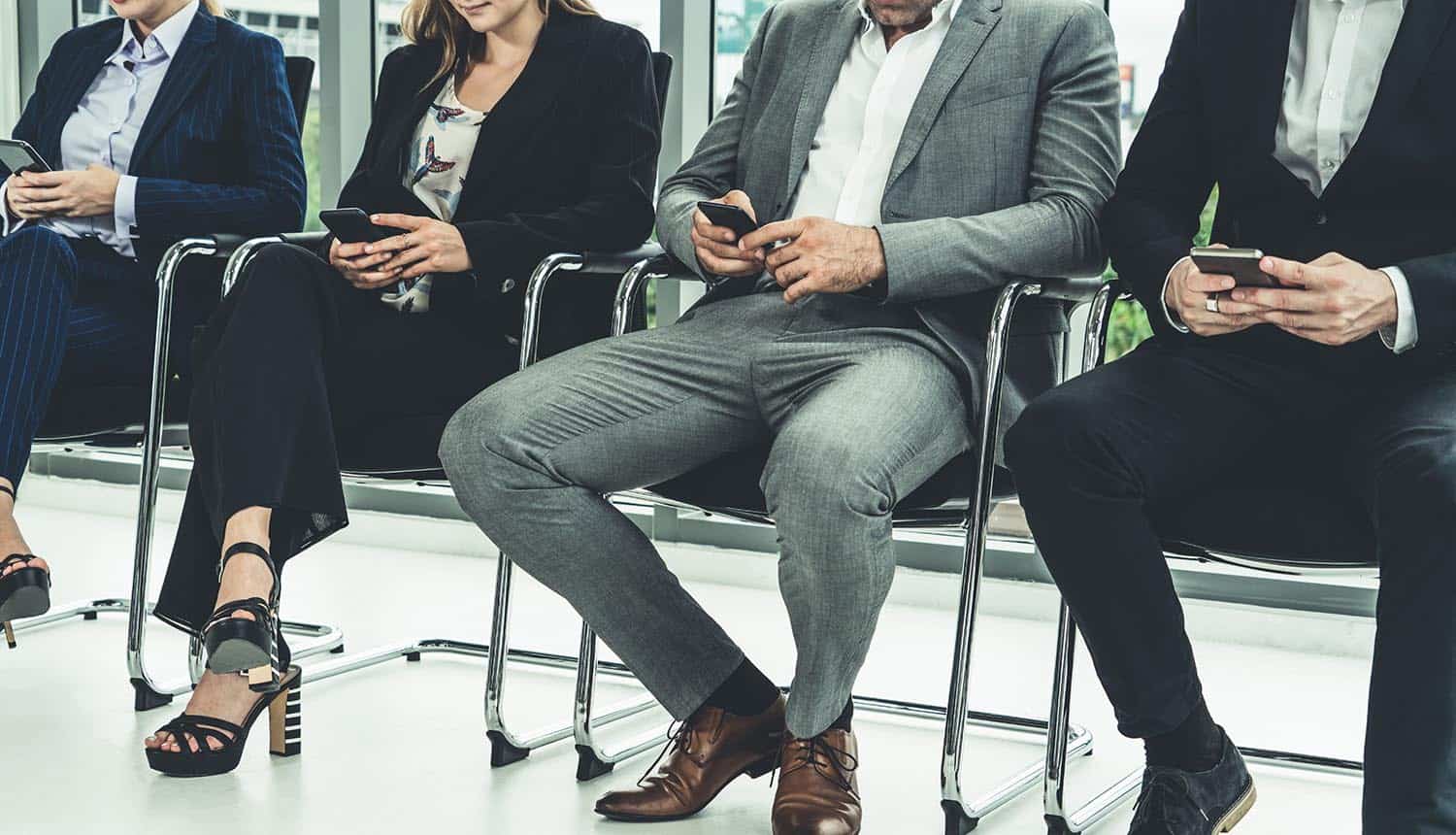 Businesswomen and businessmen using mobile phone while waiting for job interview showing demand for privacy pros