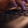 Hands typing on keyboard showing monitoring app on student computers