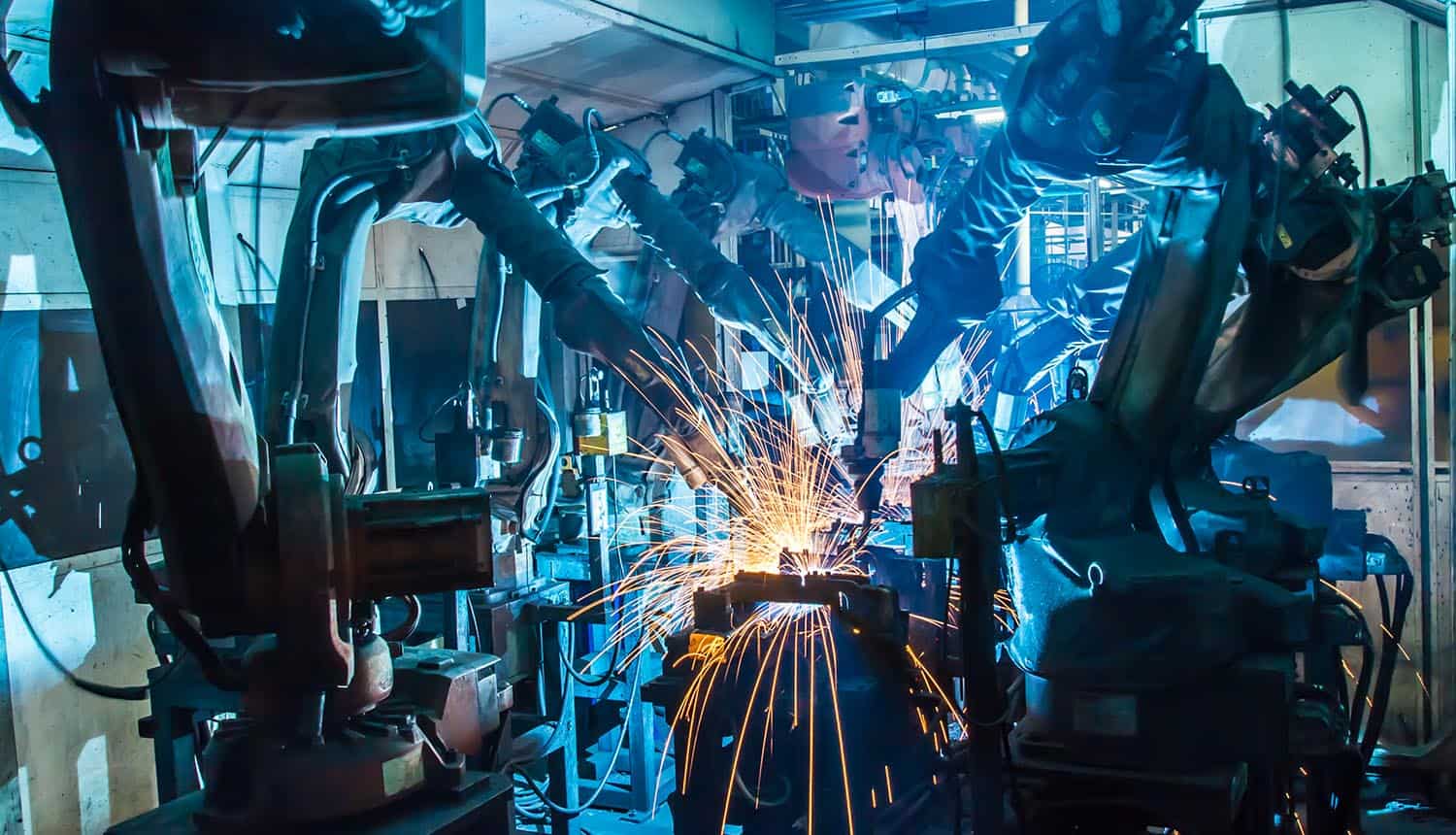 Robots welding movement in a car production factory showing IoT security and zero trust
