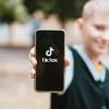 Boy holding smartphone with TikTok on the screen showing privacy lawsuit alleging violation of child privacy