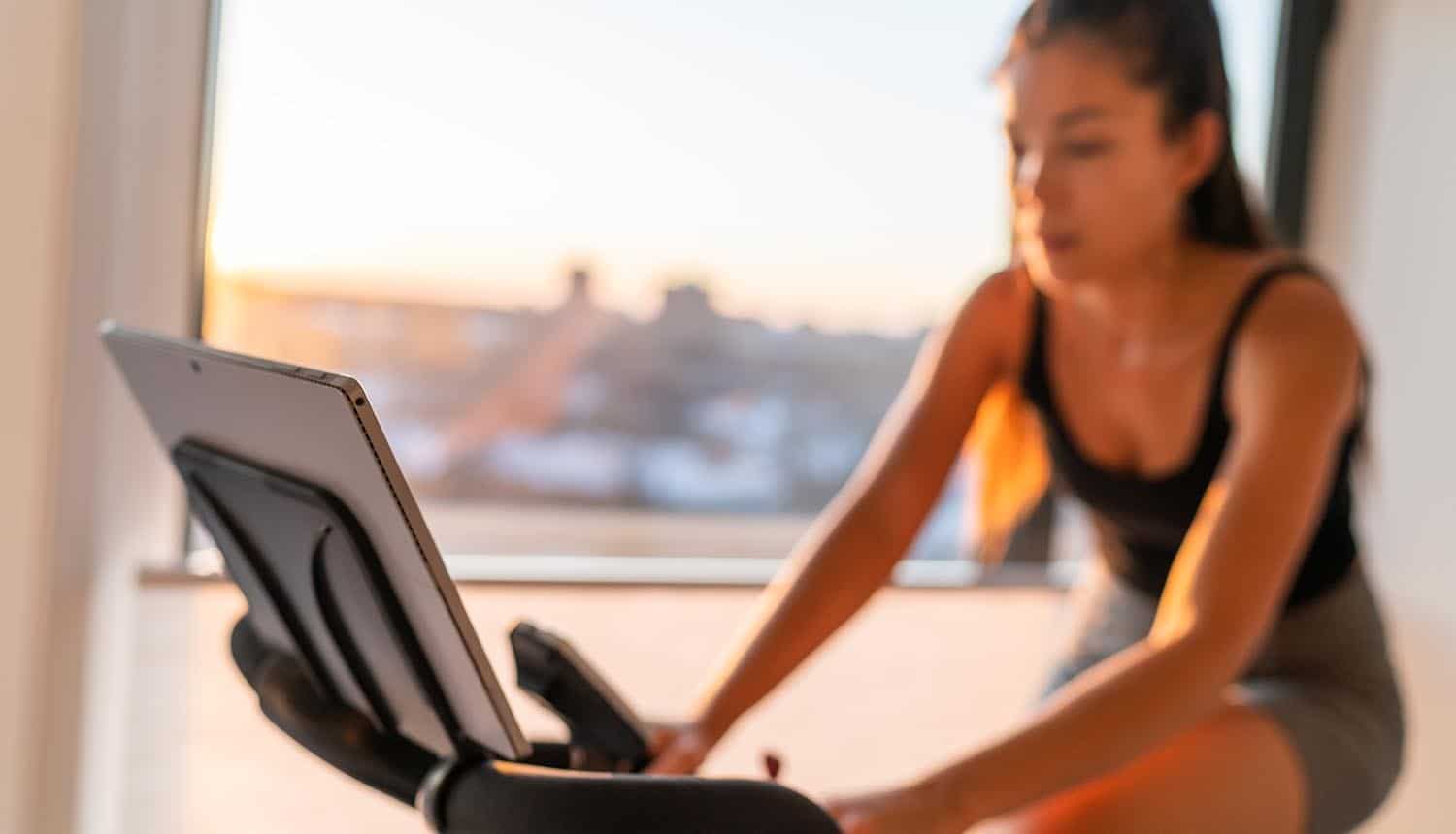 Woman exercising on smart stationary bike at home showing need for API security
