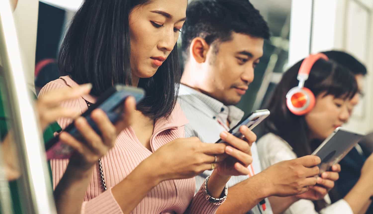 Young people using mobile phone in public underground train showing data breach by digital ad industry