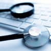 Magnifying glass lies on white keyboard on desk in office table showing detection-as-code for threat detection