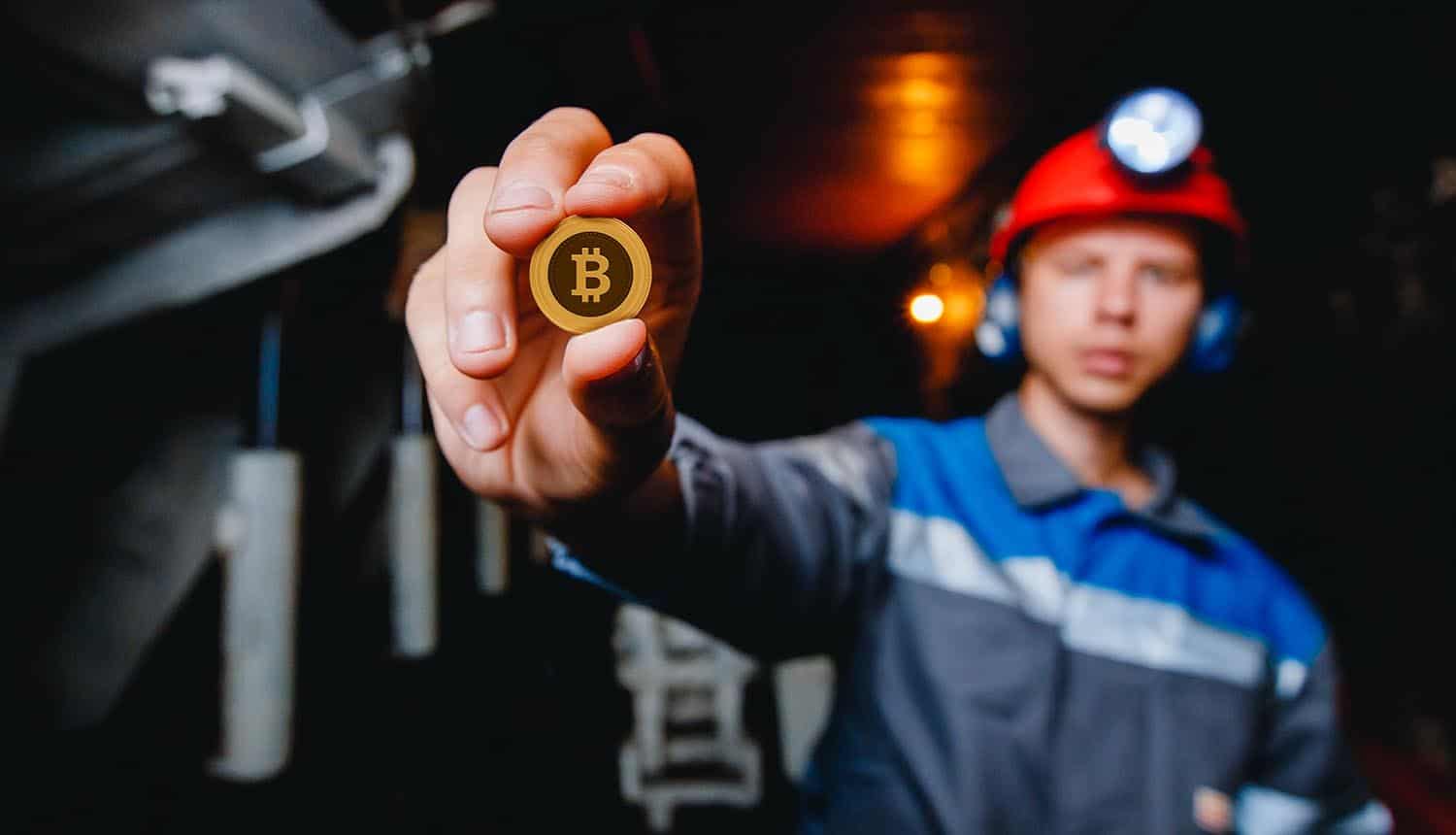 Miner holds a bitcoin in his hand