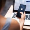 Woman in front of laptop holding phone with lock code showing privacy and security