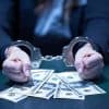 Woman in handcuffs behind bank notes showing law enforcement arrest of suspects for ransomware attacks