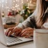 Close up of woman hands with, gifts, coffee cup and laptop showing cybersmart when holiday shopping