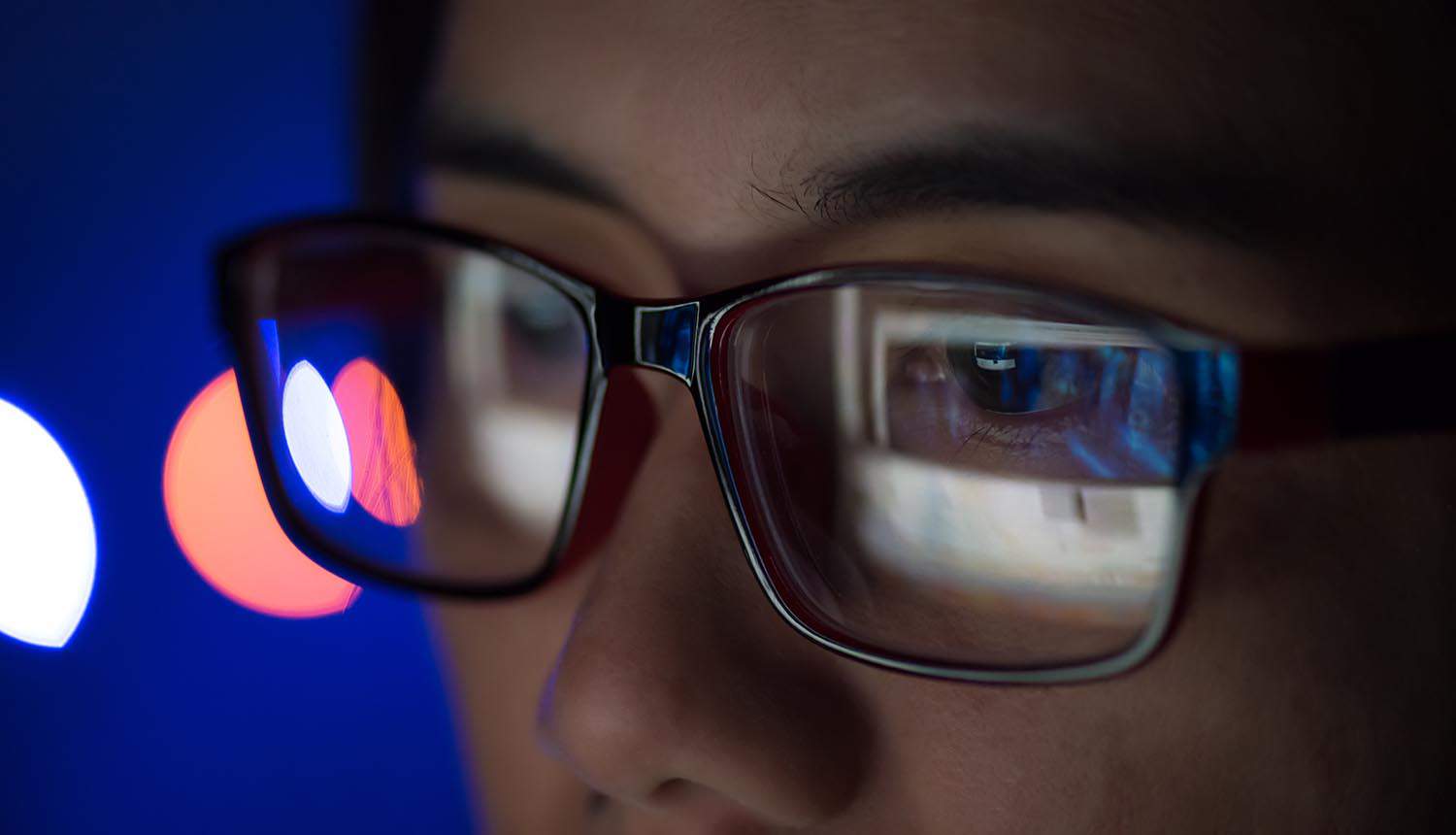 Woman wearing glasses working on the laptop showing Proxyshell vulnerability and cyber risk