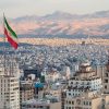 Iran flag waving above skyline of Tehran at sunset showing APT groups targeting critical infrastructure