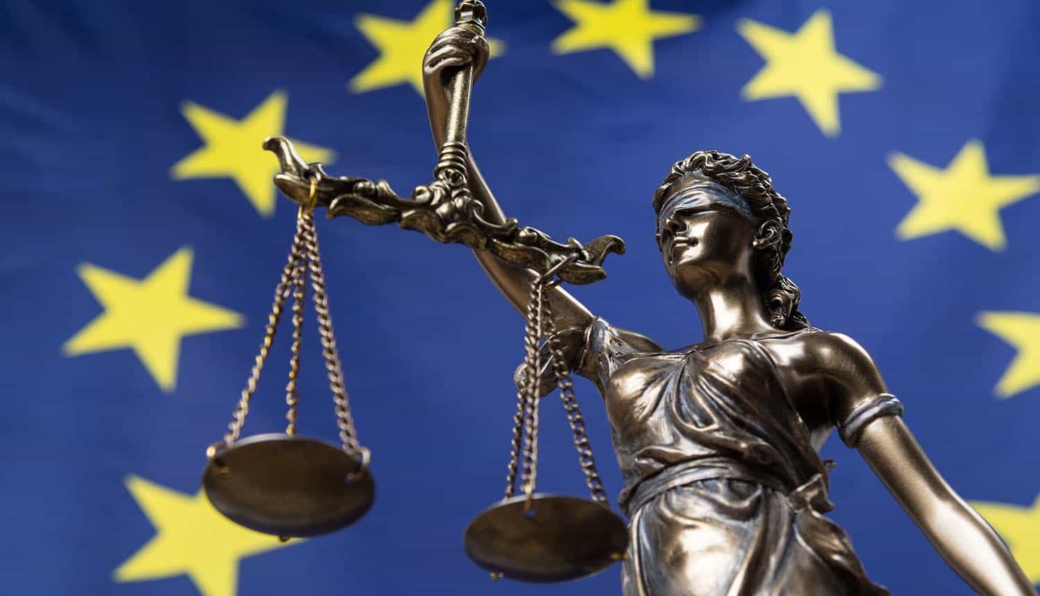 Statue of the blindfolded goddess of justice against an European flag