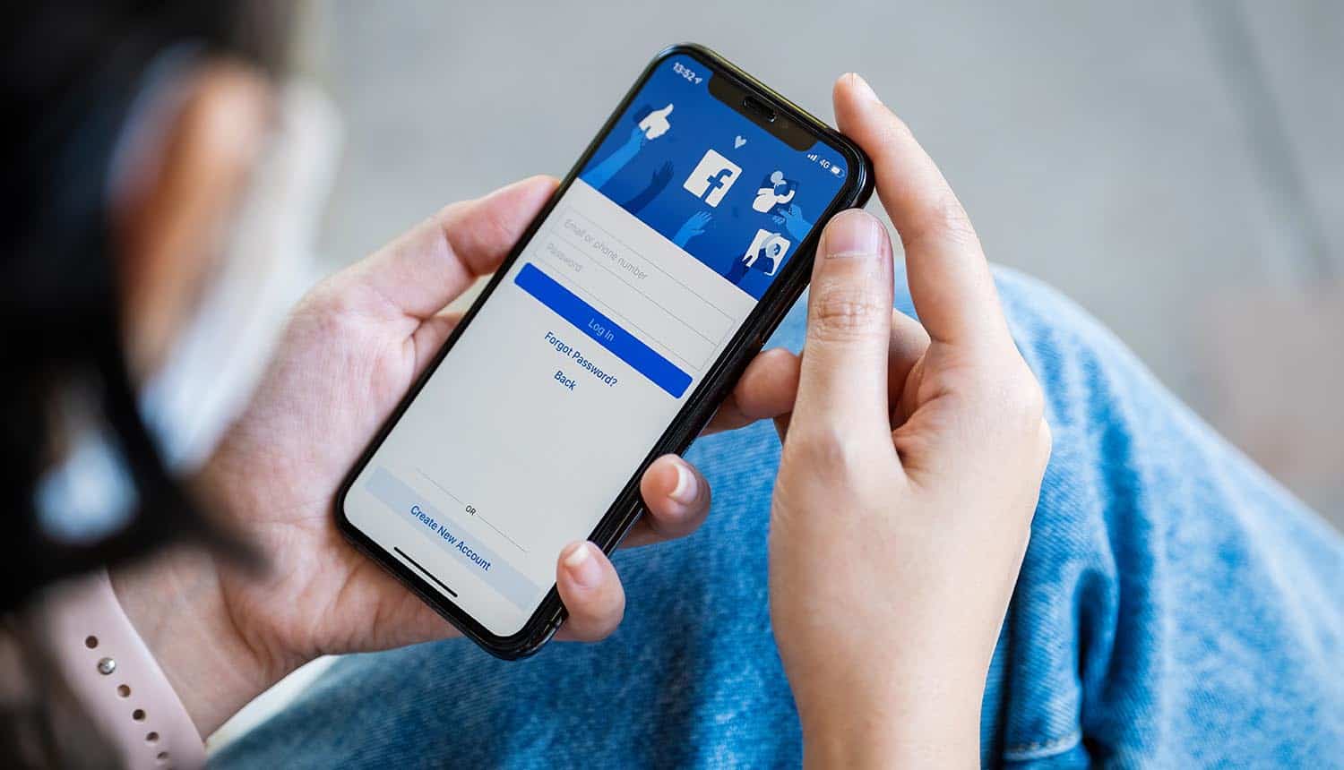 Woman holds iPhone with Facebook app on the screen showing Apple privacy rules